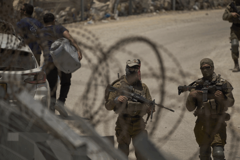 Israeli soldiers stand guard as Syrian Druze people cross back into Syria at the Israeli-Syrian border, in the Israeli-controlled Golan Heights town of Majdal Shams, on Thursday.