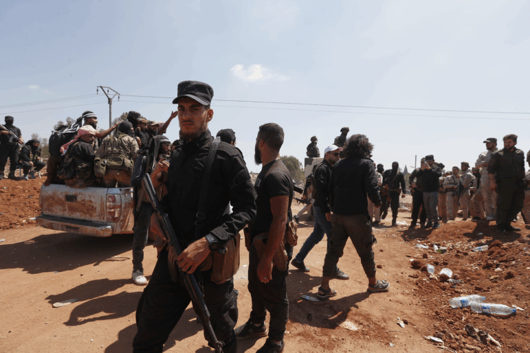 Syrian government security forces block Bedouin fighters, background, from entering Sweida province, in Busra al-Harir village, southern Syria on Sunday.