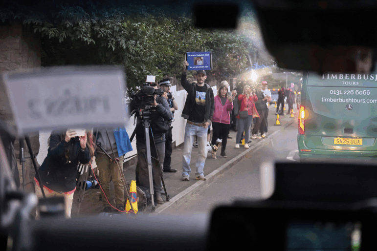 A man seen through the windshield of a moving vehicle holds up a sign reading: "This is not a paedophile island. You are not welcome here," as the motorcade of President Trump arrives at the golf course in Turnberry, Scotland, on Friday.