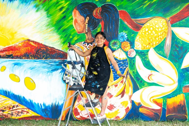 Evelyn del Rosario Morán Cojoc, an artist from Guatemala, creates a mural that depicts traditional foods from her Mayan culture — like that floating ear of corn and three yellow beans. She teaches art to kids across the country, encouraging them to depict their indigenous traditions.