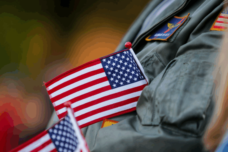 Robert Kielbowicz, who spent 4 of his 12 years in the Navy at NAS Oceana, tucks a flag into his jacket while cheering during the Veterans Day Parade in Virginia Beach, Virginia, on Nov. 11, 2024.