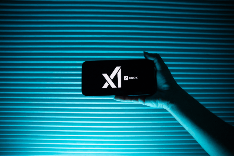 A person holds a telephone displaying the logo of Elon Musk's artificial intelligence company, xAI and its chatbot, Grok.