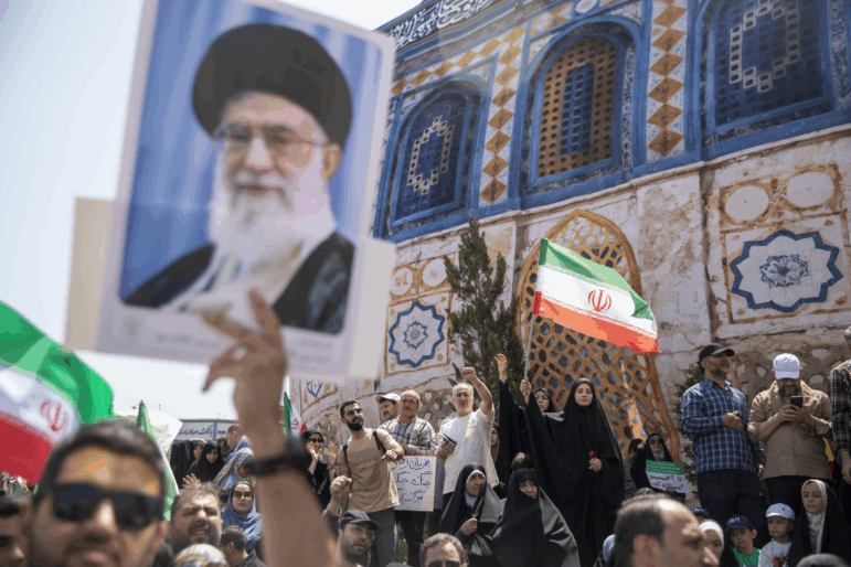 Demonstrators wave Iranian flags as one holds up a poster of Iran's Supreme Leader Ayatollah Ali Khamenei during a protest against Israeli attacks on Iran, after the Friday prayer ceremonies on June 20, 2025 in central Tehran, Iran.