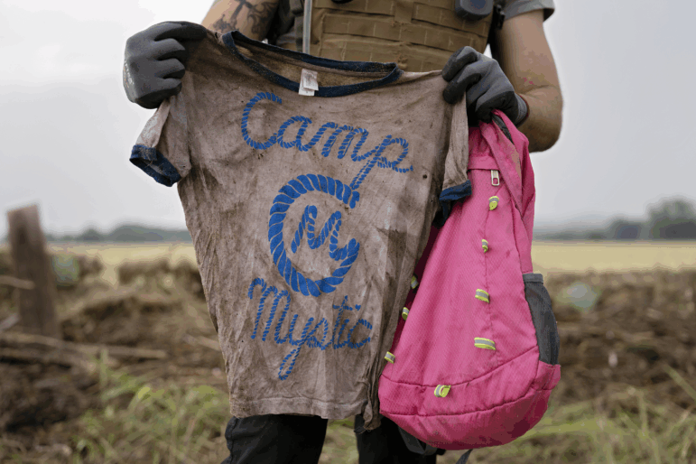 A search and rescue volunteer holds a T-shirt and backpack with the words Camp Mystic on them in Comfort, Texas on July 6, 2025. The volunteer found the belongings yesterday along the Guadalupe River near Ingram, Texas.