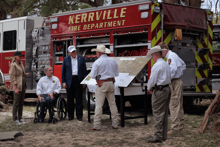 President Trump, first lady Melania Trump and Texas Governor Greg Abbott meet with local emergency services personnel as they survey flood damage along the Guadalupe River on July 11, in Kerrville, Texas.