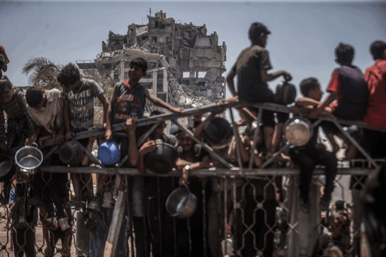 Displaced Palestinians wait for food in front of a charity kitchen in Gaza City on July 28, 2025.