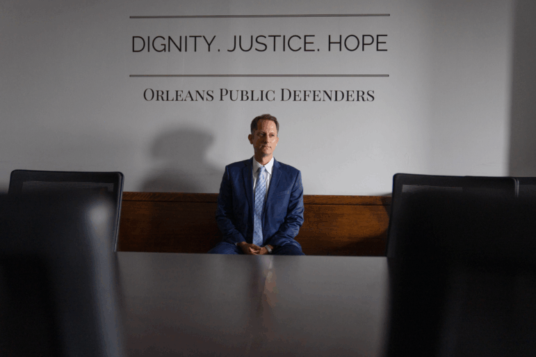 Danny Engelberg, head of Orleans Public Defenders, sits for a portrait in their offices. The words on a wall behind him say: Dignity. Justice. Hope.