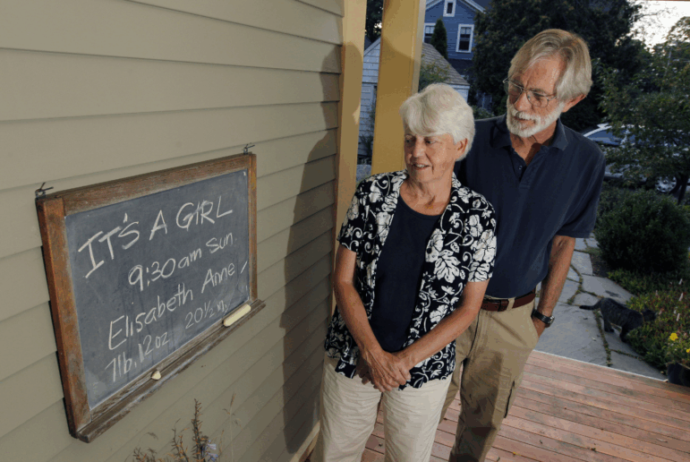 Eileen and Doug Flockhart look at a chalkboard announcing the birth of their seventh grandchild on the porch of their home in Exeter, N.H., Wednesday, Aug. 24, 2011.
