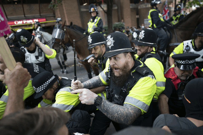 Mounted police officers scuffle with demonstrators during a protest by anti-migrant Abolish Asylum System and counter protesters at Castle Park in Bristol, England on Saturday.