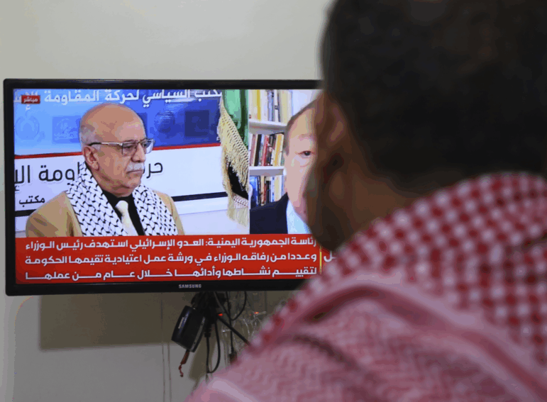 A man watches the news on TV, displaying footage of Ahmed al-Rahawi, the prime minister of the Houthi-controlled government, who was killed, along with others, in Thursday's Israeli strikes on the capital, in Sanaa, Yemen, Saturday, Aug. 30, 2025.