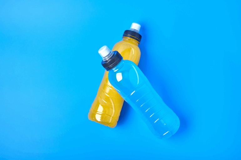 Orange and blue sports drink in plastic bottles on a blue background.