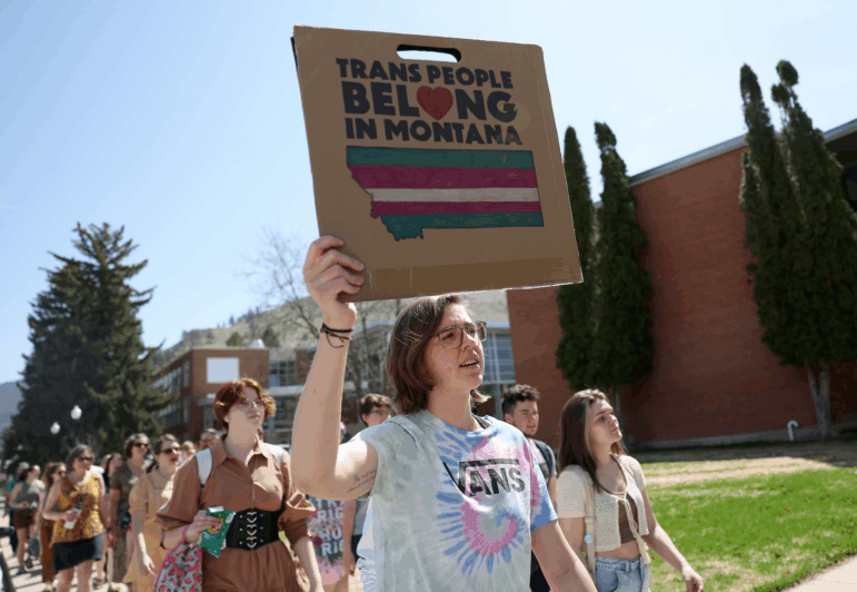 Transgender rights activists hold signs as they march through the University of Montana campus on May 03, 2023 in Missoula, Mont.