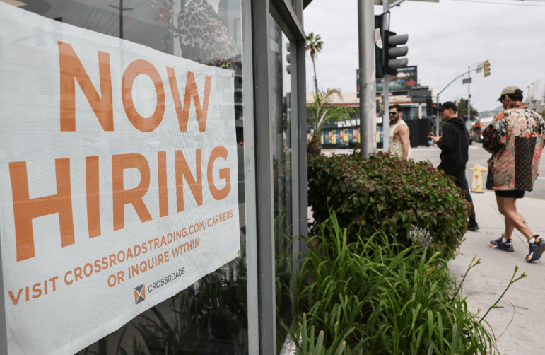 A 'Now Hiring' sign is displayed outside a resale clothing shop.