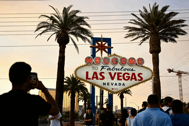 People take pictures with the Welcome To Fabulous Las Vegas sign under hazy orange skies as the sun sets on July 29, 2023.