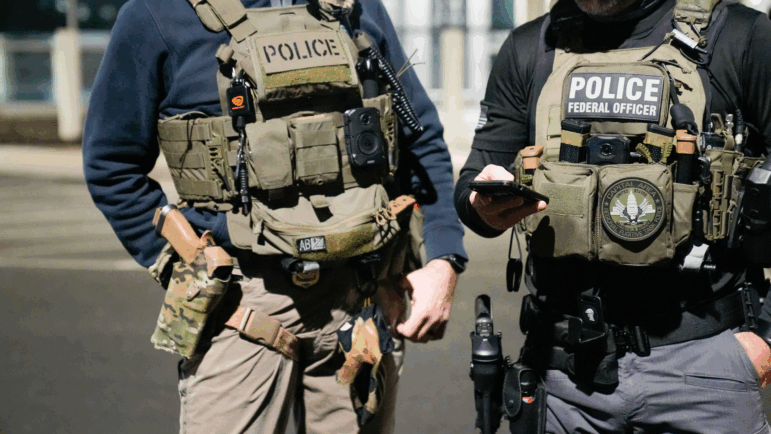 In this handout photo provided by U.S. Immigration and Customs Enforcement, two federal law enforcement officers coordinate with other officials during an enforcem February 4, 2025 near Washington, D.C. (Photo by U.S. Immigration and Customs Enforcement via Getty Images)