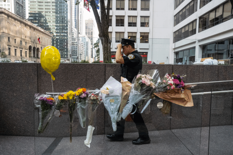 NEW YORK, NEW YORK - JULY 29: A New York City police officer walks past flowers placed outside the midtown office building where a gunman killed four people on July 29, 2025 in New York City.  (Photo by Stephanie Keith/Getty Images)
