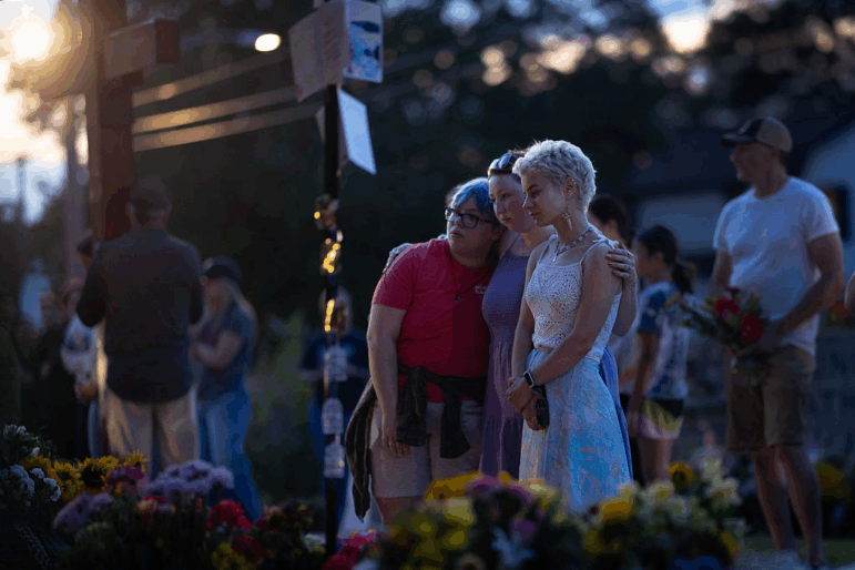 People gather at a memorial for victims of Wednesday's shooting at Annunciation Catholic Church in south Minneapolis. Two children were killed and 18 other people were injured.