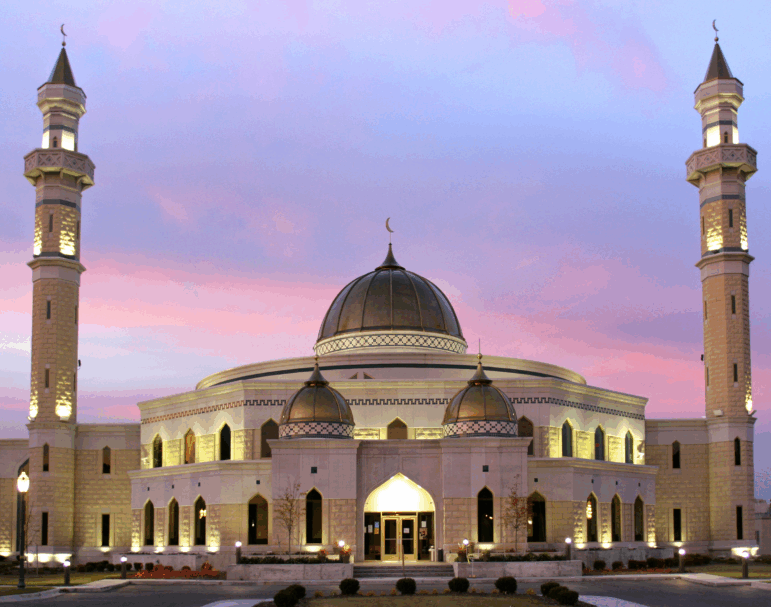 The Islamic Center of America mosque is lit up against the backdrop of a colorful sunset.