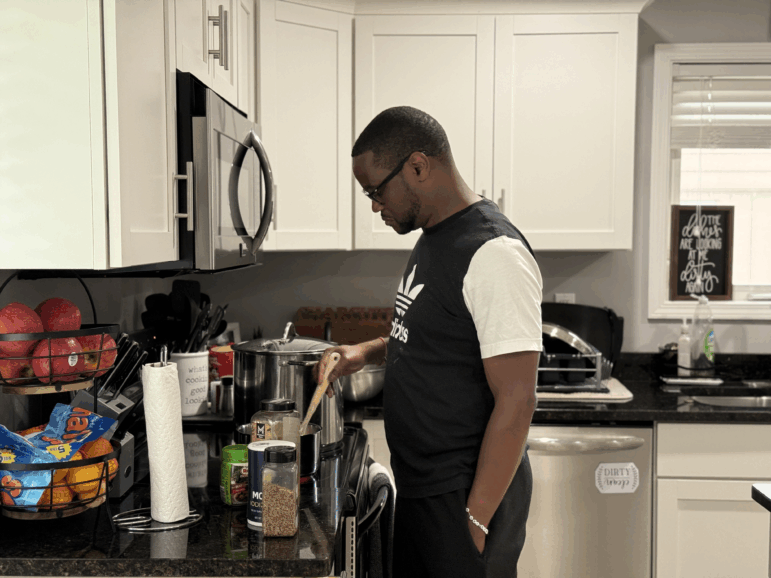 Samuel Kangethe cooks in his home on July 3, 2025, in Lansing, Michigan.