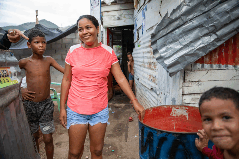 In La Paz, a low-income neighborhood on the outskirts of Santa Marta, Colombia, water service from the local utility can be erratic or nonexistent. Pictured: Neighborhood kids stand next to a rain barrel positioned under a corrugated roof.
