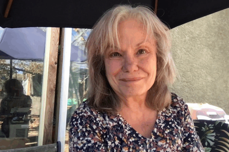 Juli Cobb in 2024. She's seated outdoors and is photographed from about the shoulders up. She has shoulder-length hair and is wearing a multicolored top.