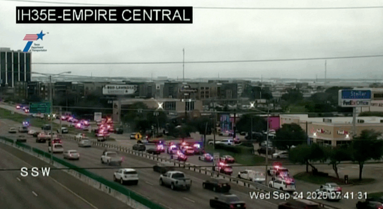 Police cars and ambulances wait outside an Immigration and Customs Enforcement detention facility in Dallas where a shooting took place on Wednesday, in this screenshot from a Texas Department of Transportation traffic camera video.