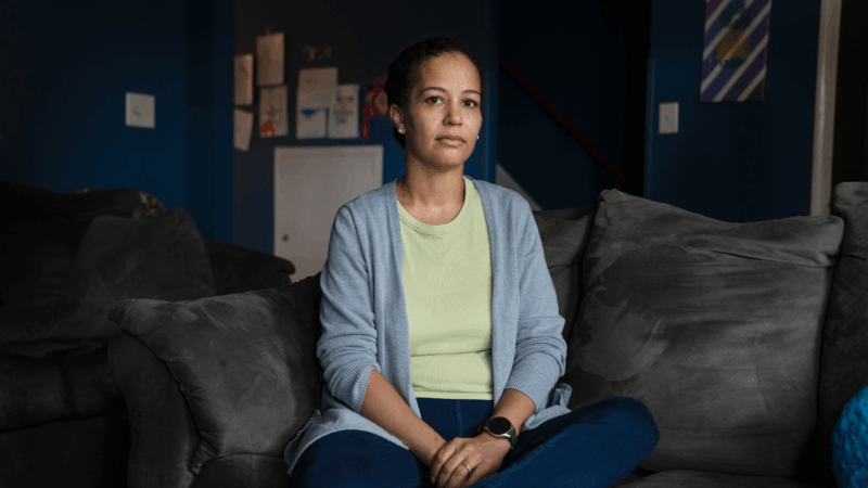 Stephani Cherkaoui sits cross-legged on a gray sofa. She's wearing blue jeans, a light-colored shirt and a light blue cardigan.