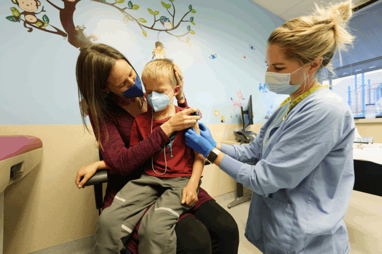 Jill Holm-Denoma holds her son, Tyler, after he received a COVID shot in 2021 from nurse Emily Cole at National Jewish Health in Denver. After President Trump appointed anti-vaccine activist Robert F. Kennedy, Jr. to be Secretary of Health and Human Services, Colorado updated state laws to ensure continued access to the COVID shot and other vaccines.