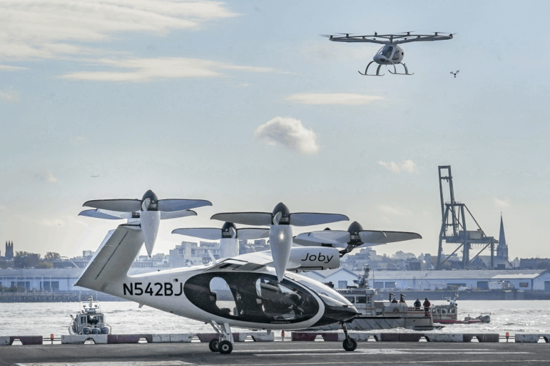 An electric vertical takeoff and landing (eVTOL) aircraft, flies above the Joby eVTOL aircraft, during a demonstration of eVTOLs Nov. 13, 2023, in New York.