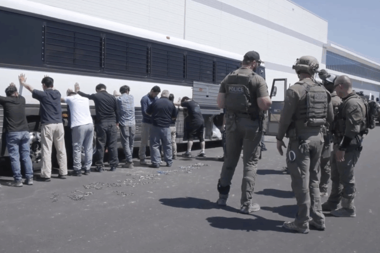 This image from video provided by U.S. Immigration and Customs Enforcement via DVIDS shows manufacturing plant employees waiting to have their legs shackled at the Hyundai Motor Group’s electric vehicle plant, Thursday, Sept. 4, 2025, in Ellabell, Ga.