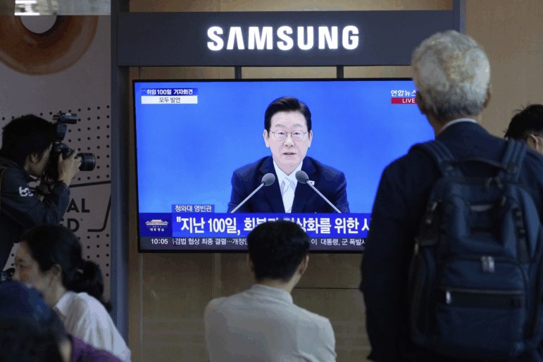 People watch a TV screen showing the live broadcast of South Korean President Lee Jae Myung's press conference at the Seoul Railway Station in Seoul, South Korea, Thursday, Sept. 11, 2025.