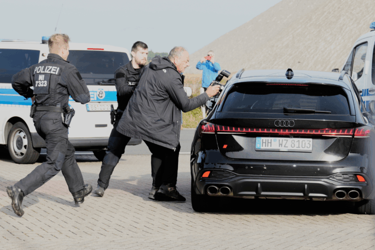 Police officers try to stop a British photographer as he takes pictures inside a car leaving a prison, carrying a suspect in the 2007 disappearance of British toddler Madeleine McCann, in Sehnde, Germany, Wednesday, Sept. 17, 2025.