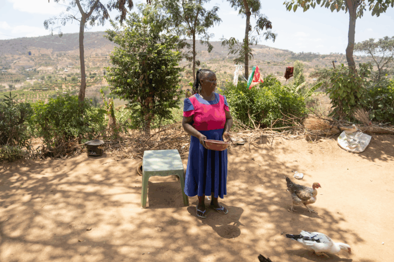Joyce Mutisya, who has dementia, feeds the birds she is raising outside her home in Wote, Kenya.