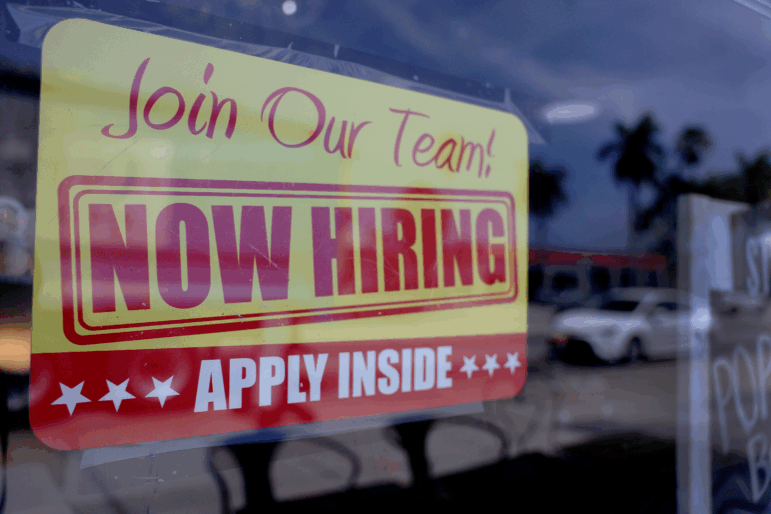 A sign in a window says "Join our team. Now hiring. Apply inside." Hiring was slower in the year ending in March than initially reported, according to a preliminary revision from the Labor Department Tuesday. The update is part of a routine process of incorporating more complete, but less timely data.