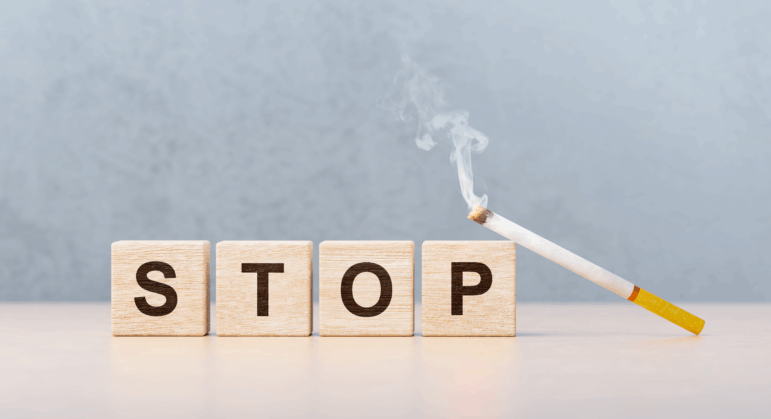 Scrabble letters spell the word "stop" next to a lit cigarette in this photo illustration.