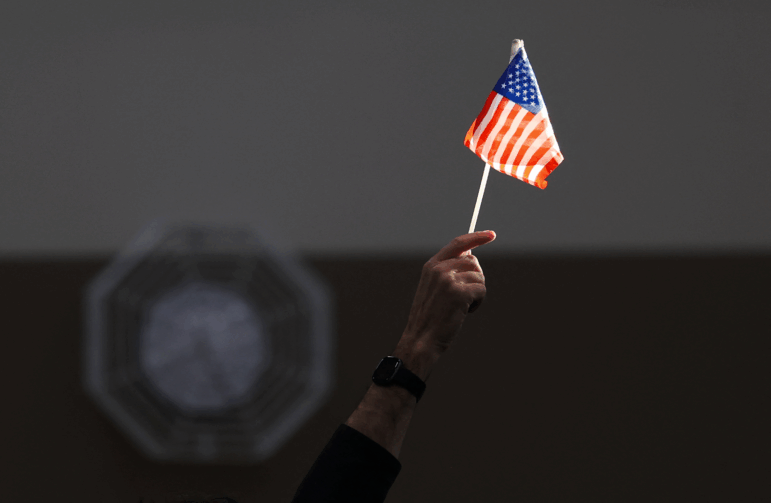 An election worker raises a U.S. flag while assisting voters at a polling station in Las Vegas on Election Day, Nov. 5, 2024.