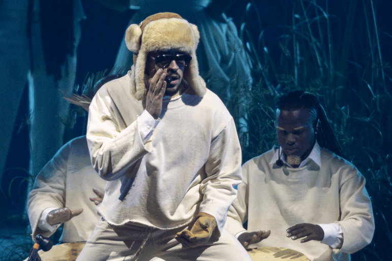 Singer and rapper Bad Bunny standing on stage with supporting musicians.