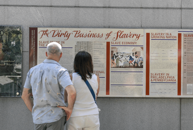 Tourists read a display titled "The Dirty Business of Slavery" at the President's House in Philadelphia on Aug. 9. Thirteen separate panels at the site are under review by the National Park Service for potential removal or editing.