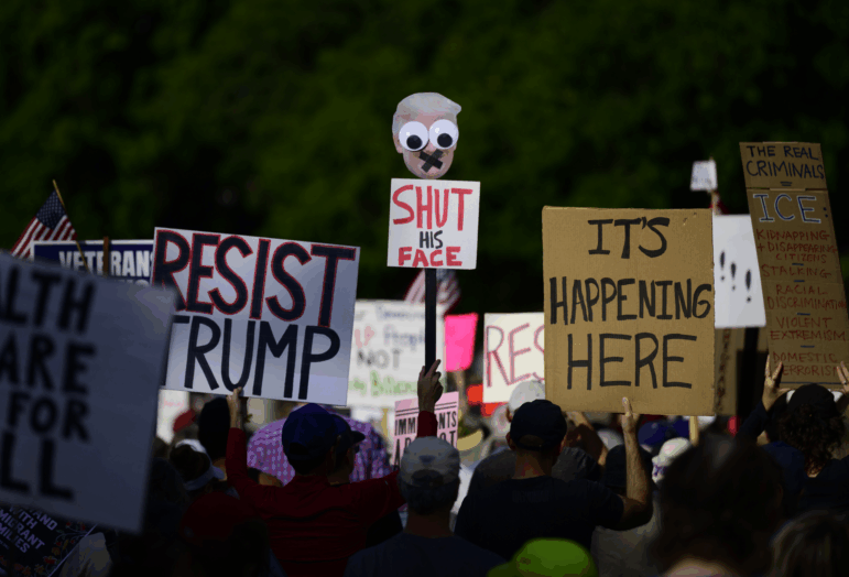 Protesters hold signs during a protest at Battleship Oregon Marine Park on September 28, 2025 in Portland, Oregon.