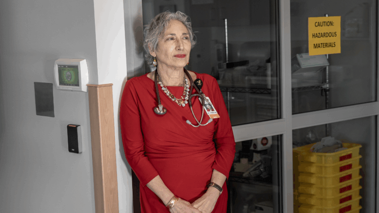 Dr. Banu Symington stands in a medical office with a stethoscope around her neck.