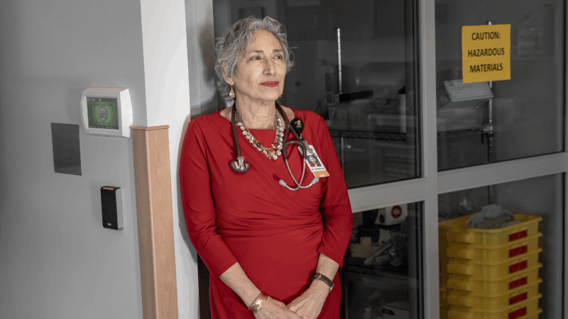 Dr. Banu Symington stands in a medical office with a stethoscope around her neck.