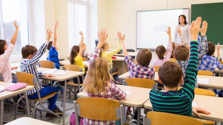 Classroom with children raising their hands