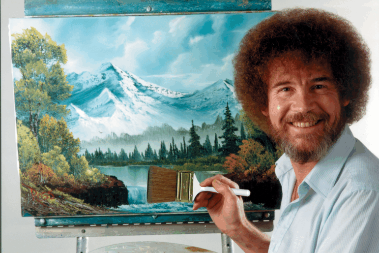 Bob Ross poses in front of one of his signature landscapes.