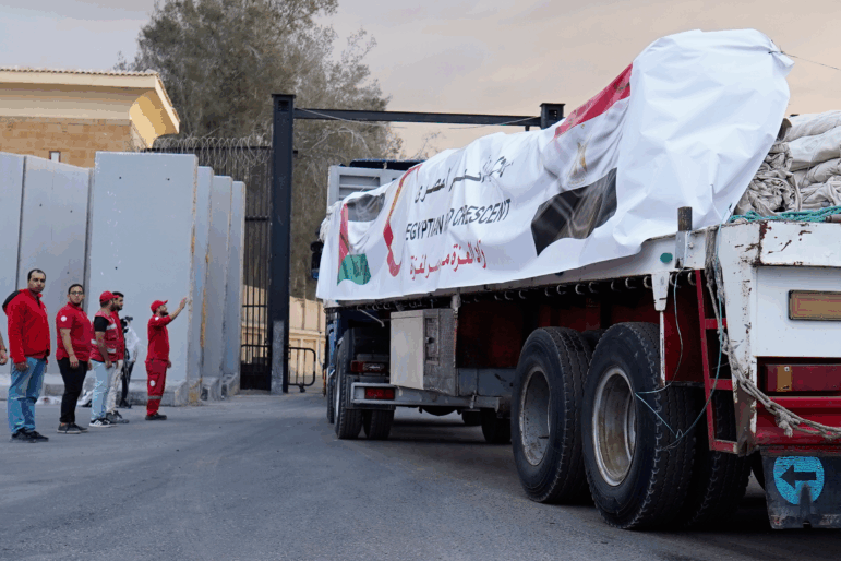 Egyptian Red Crecent members monitor trucks carrying humanitarian aid as they enter the Rafah crossing between Egypt and the Gaza Strip, following an agreement between Israel and Hamas on a ceasefire, Sunday, Oct. 12, 2025.