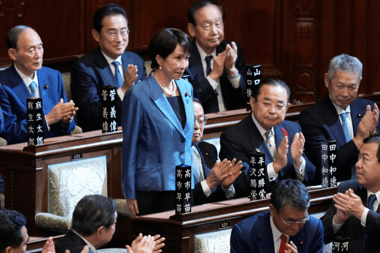 Lawmakers applaud as Sanae Takaichi, standing, was elected as Japan's new prime minister during the extraordinary session of the lower house, in Tokyo, Oct. 21, 2025.