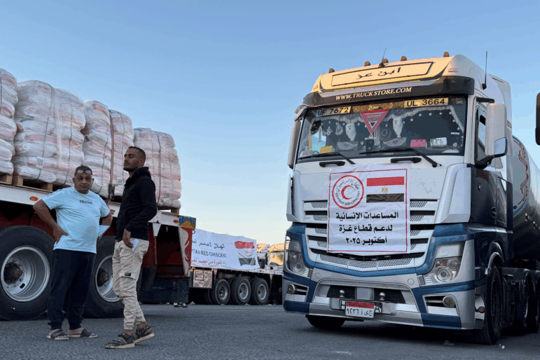 Trucks loaded with humanitarian aid on the Egyptian side of the Rafah crossing wait to cross into the Gaza Strip early on Oct. 15, 2025.
