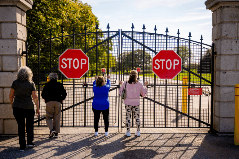 A group of friends and family traveling on a road trip, Harriett Green of Milford, New Jersey, Eveyn Hauck of Bangor, Pennsylvania, Colleen Abahazy of Easton, Pennsylvania, and Sharon Reuss of Easton, Pennsylvania, look through the locked gate to Fort McHenry National Monument and Historic Shrine on October 3, 2025 in Baltimore, Maryland. The fort is closed due to the government shutdown that began early Wednesday after Congress failed to reach a funding deal.