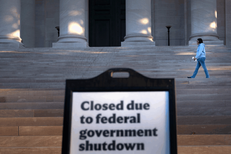 A woman walks past a sign indicating the National Gallery of Art in Washington, D.C., is closed as the federal government continues its shutdown.