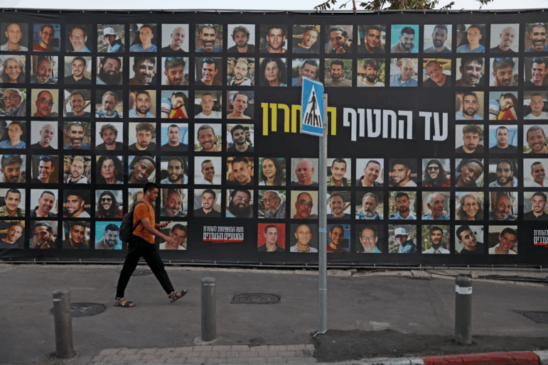 A man walks past a billboard bearing the portraits of Israelis held hostage in the Gaza Strip by Palestinian militants since Oct. 2023