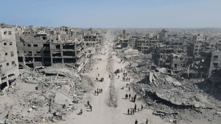People walk amid the destruction in Gaza City on Oct. 11, 2025, a day after a ceasefire took effect. Israel declared a ceasefire in Gaza and began to pull back its forces on Oct. 10, and tens of thousands of Palestinians made their way back to their devastated homes.